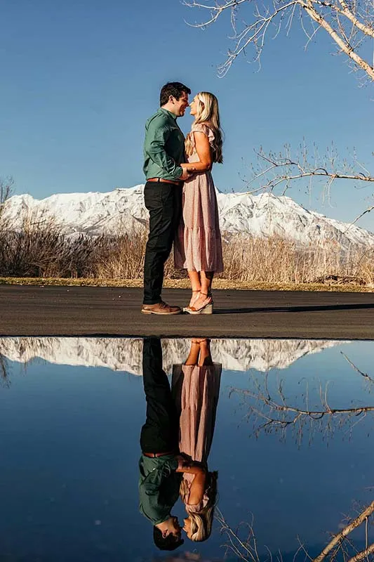 Engagment photoshoot. Couple looking at each other with reflection of the mountain at Utah lake